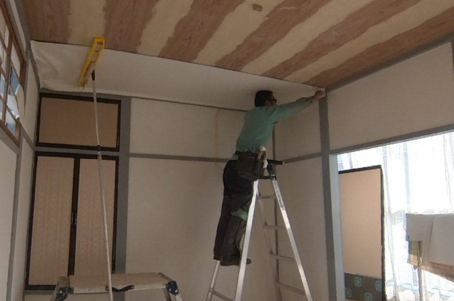 脚立を使った天井への壁紙貼り